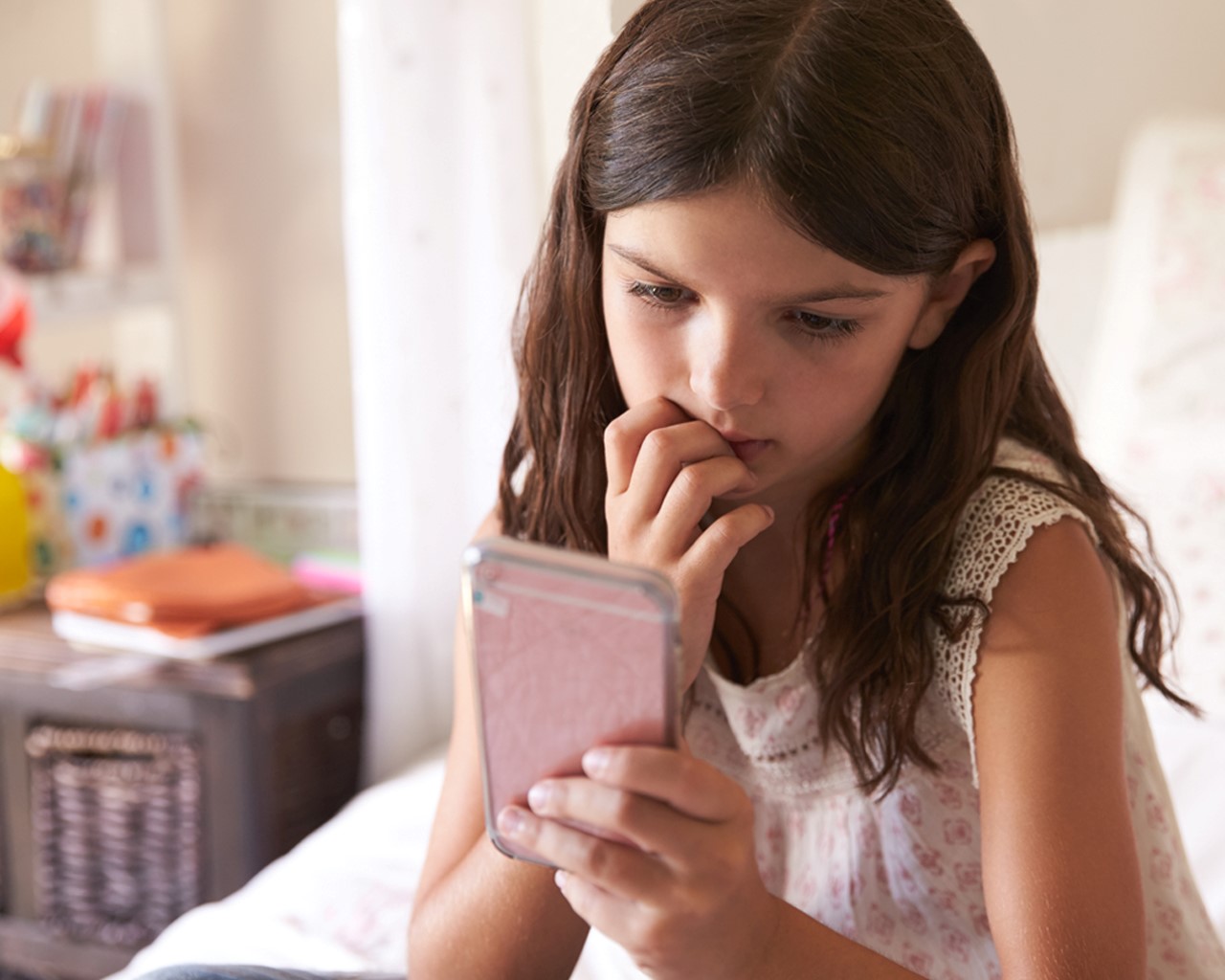 A child views her mobile phone with a worried expression