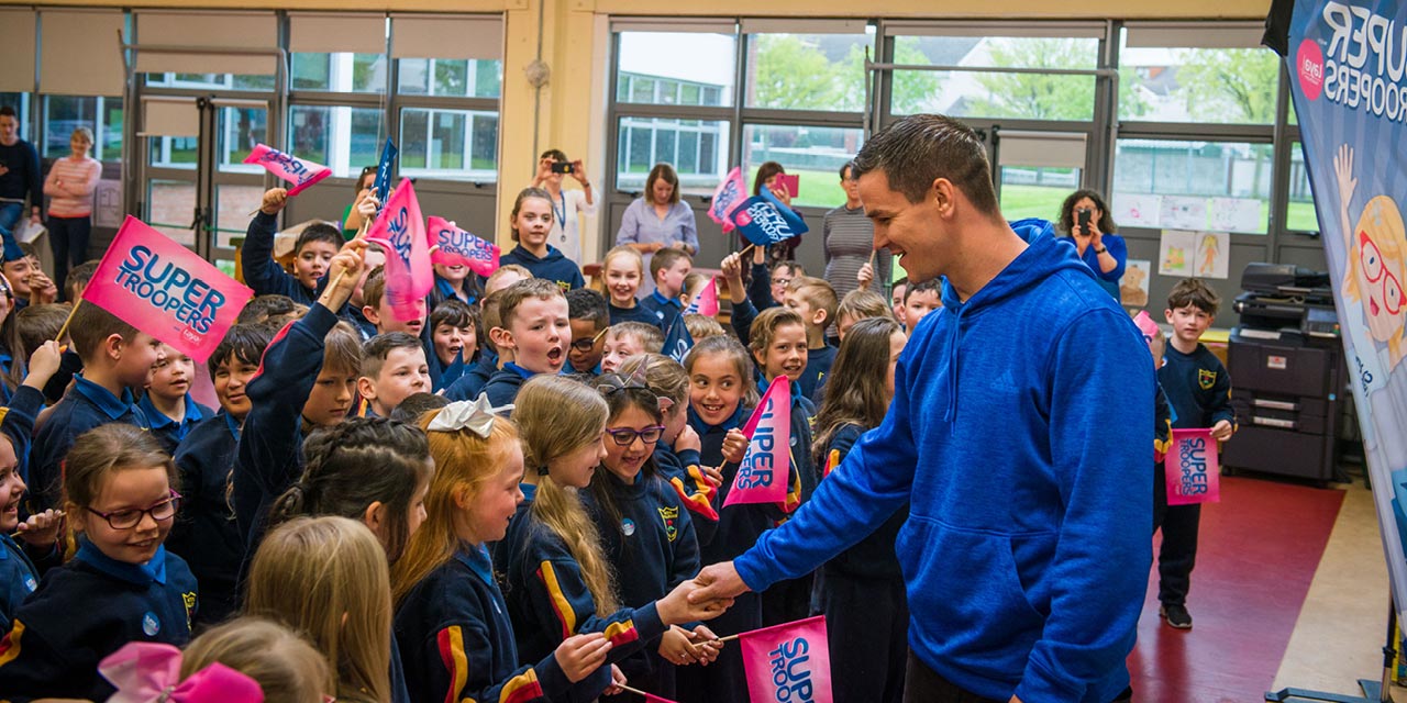 Johnny Sexton is greeted by a group of flag waving children in Scoil Maelruain, Tallaght.