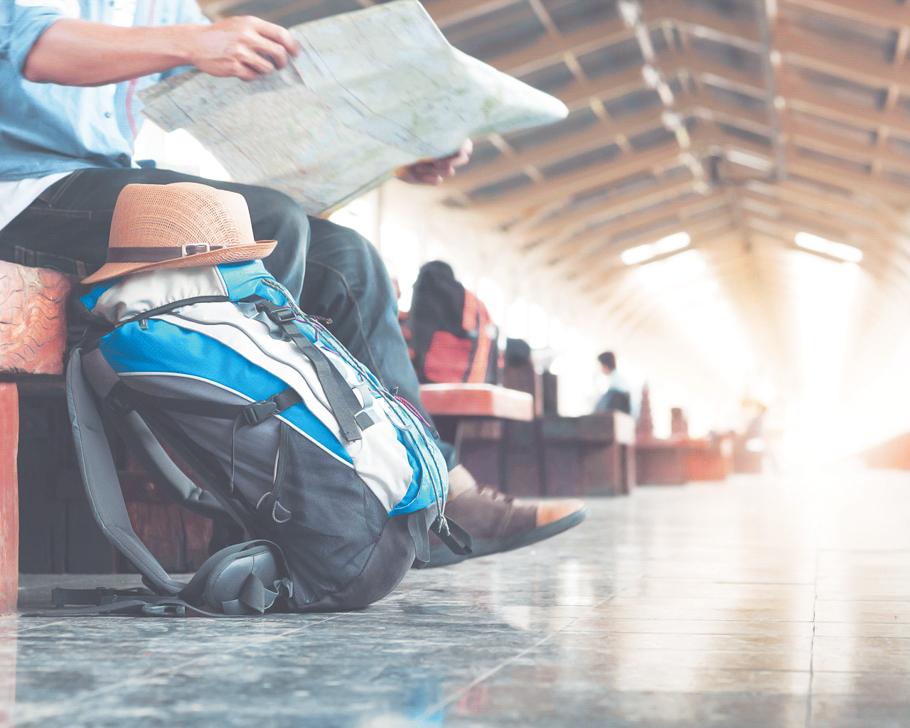 Image of backpacker waiting in train station, reading map