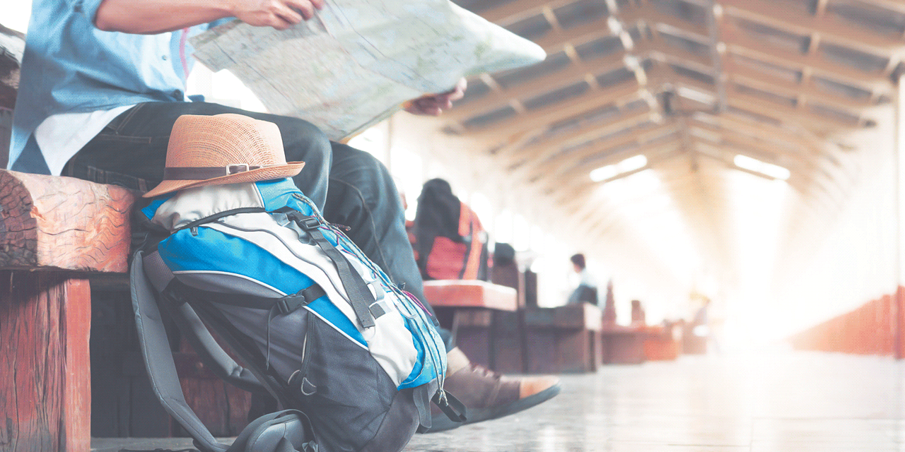 Image of backpacker waiting in a station, reading a map
