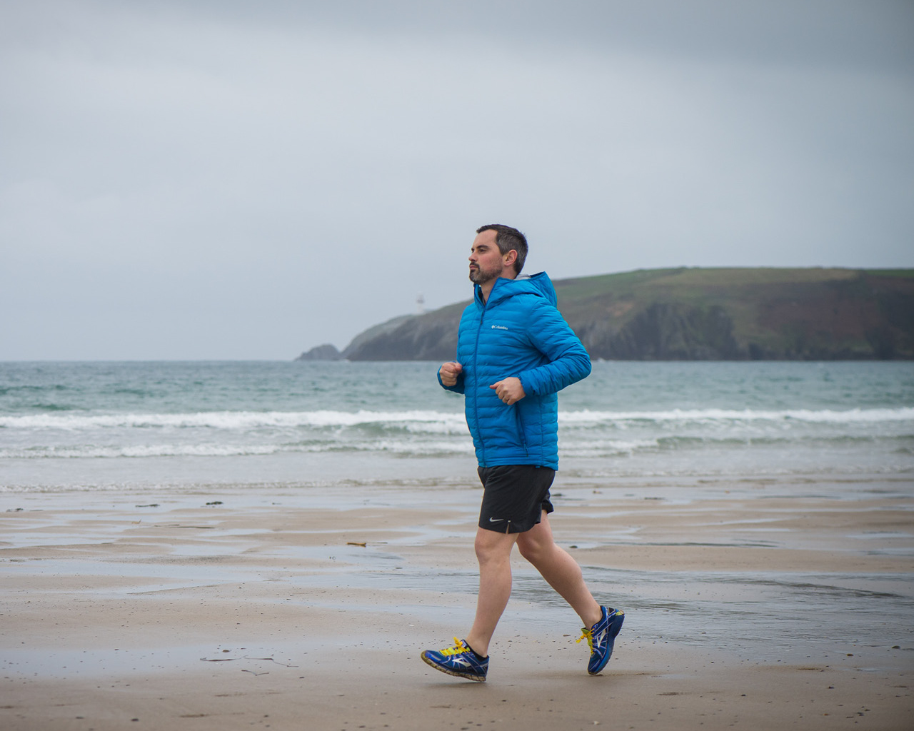 Karl Henry in a blue top, running on a beach
