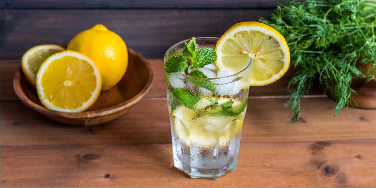 Bowl of lemons, glass of water with lemons on a table