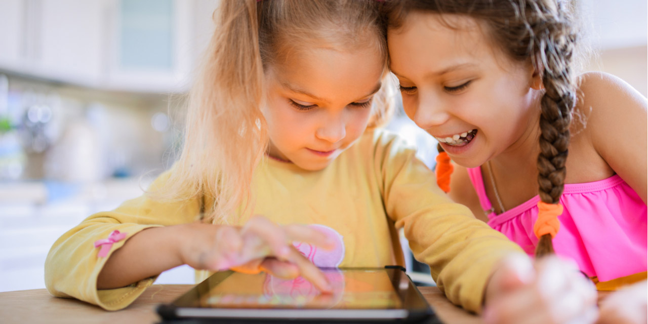 Two children play happily on a tablet