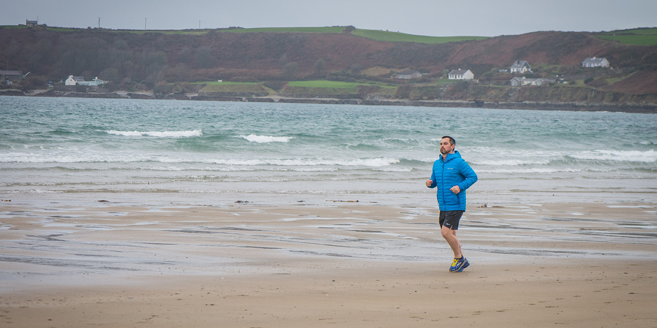 Karl Henry in a blue top, running on a beach