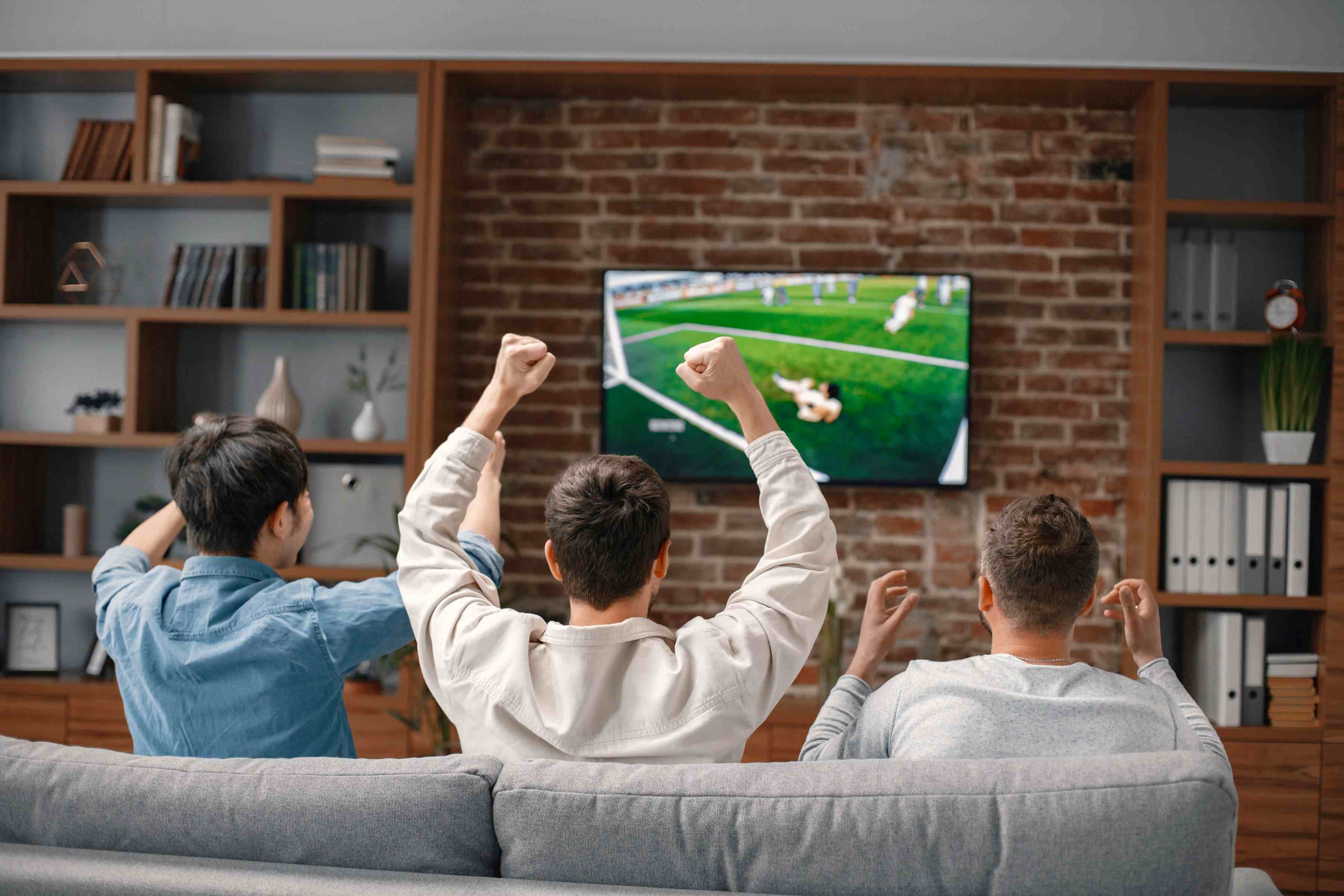 Three men watching a soccer match at home